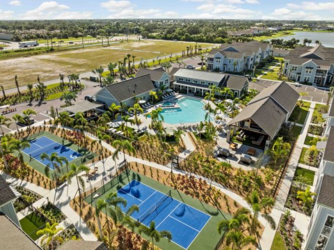 A large building complex with a tennis court in the foreground.