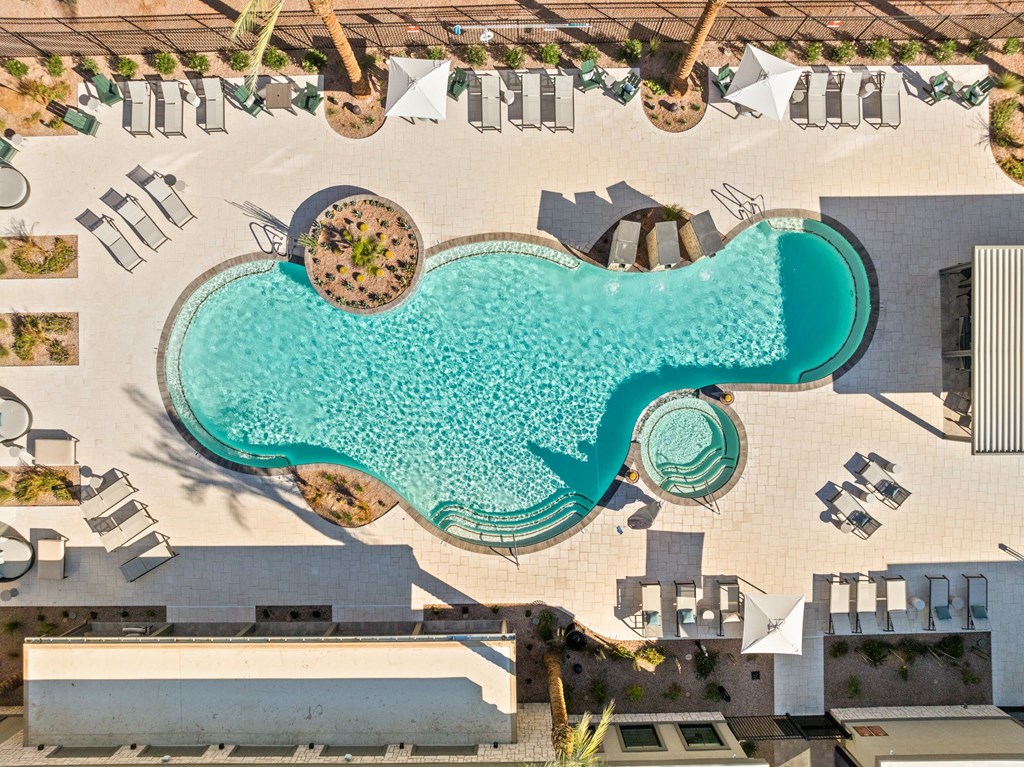 A large swimming pool surrounded by lounge chairs and umbrellas. at The Maddox Luxury Apartments, Buckeye, AZ, 85326