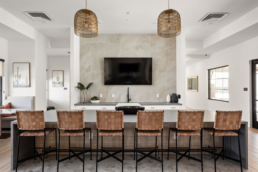 A modern kitchen with a bar area and chairs. at The Maddox Luxury Apartments, Buckeye, AZ, 85326