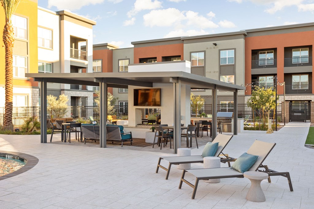 A patio with chairs and a table in front of apartment buildings. at The Maddox Luxury Apartments, Buckeye, AZ, 85326