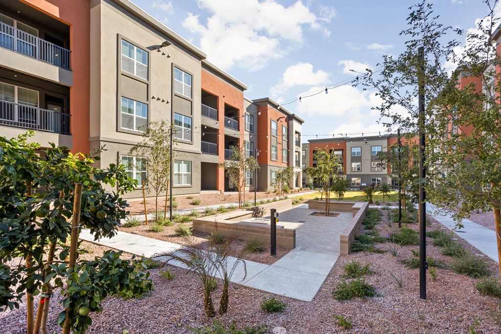 A modern apartment complex with a courtyard and trees. at The Maddox Luxury Apartments, Buckeye, AZ, 85326