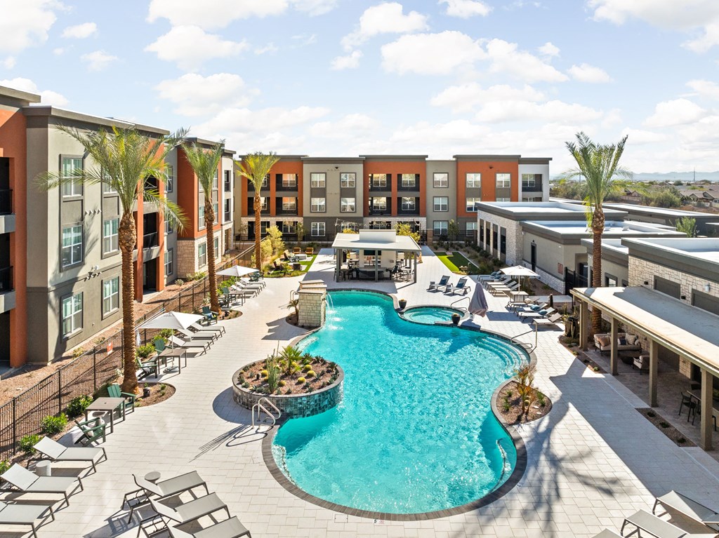 A large swimming pool surrounded by lounge chairs and palm trees at The Maddox Luxury Apartments, Buckeye, AZ, 85326