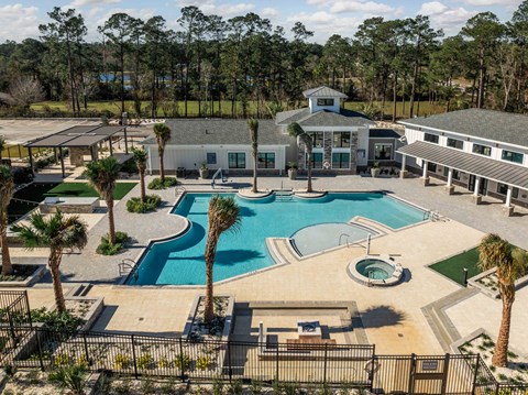 A large swimming pool surrounded by palm trees and a building in the background.