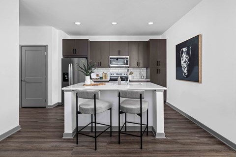 A kitchen with a table and chairs in front of a refrigerator.