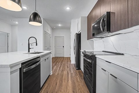 A modern kitchen with white countertops and black appliances.