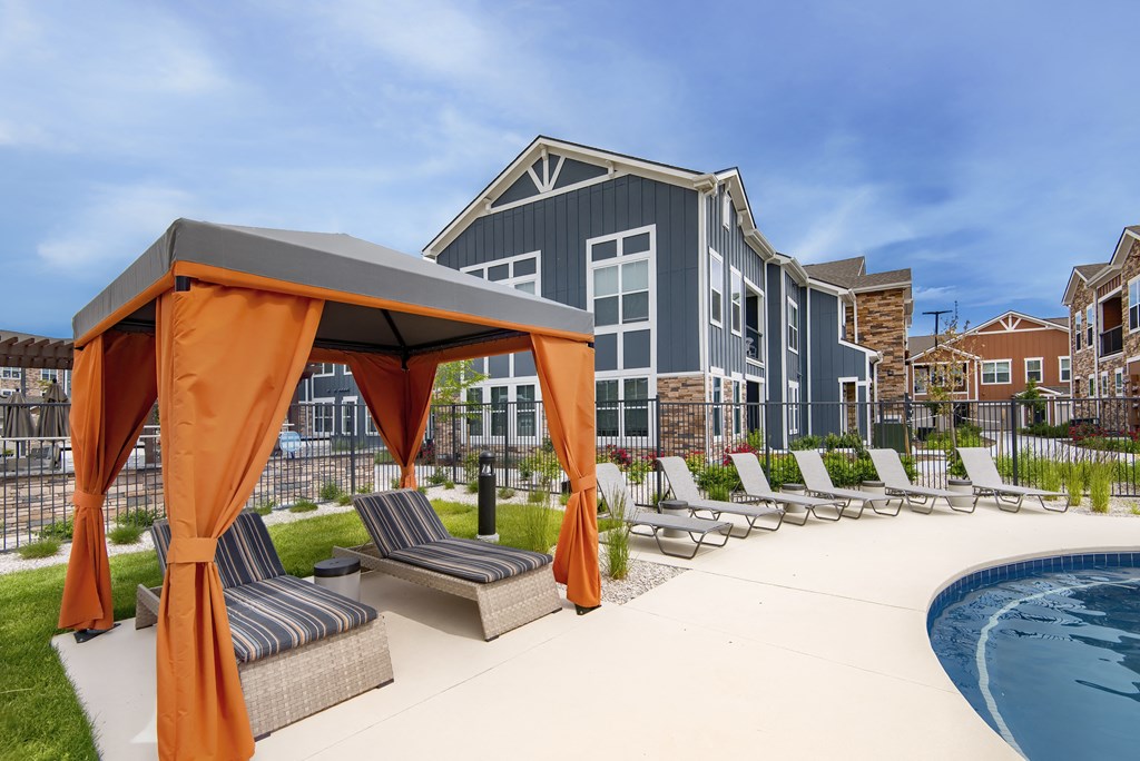 an outdoor pool with lounge chairs and a building in the background at Watermark on Twenty Mile, Colorado 80134
