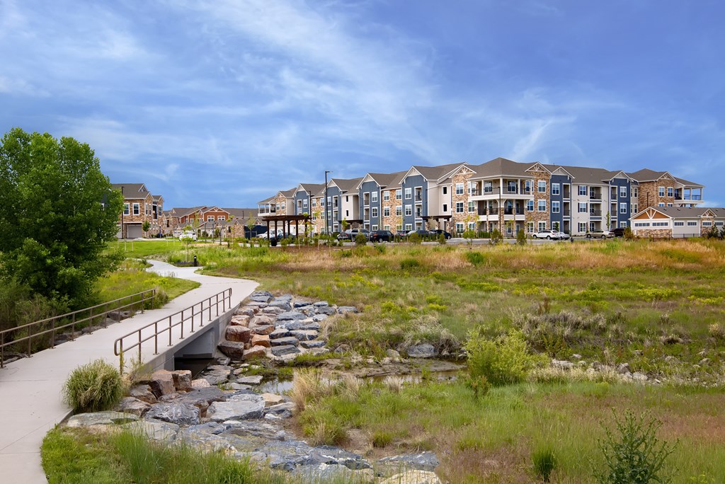 a bridge over a creek in front of an apartment building at Watermark on Twenty Mile, CO