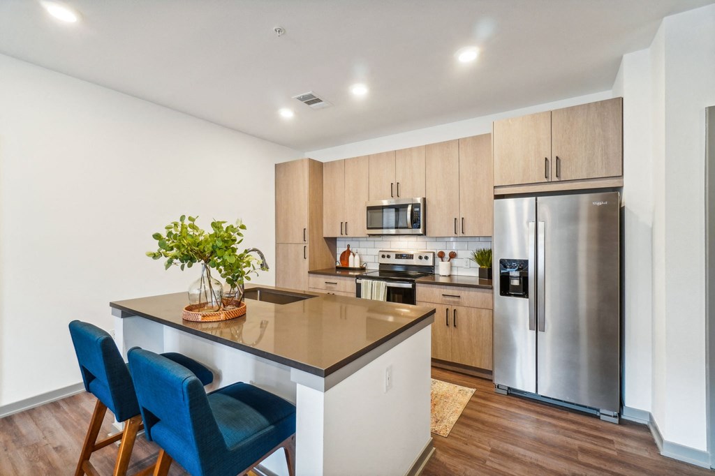a kitchen with a large island and a stainless steel refrigerator at Premier at West Park Luxury Apartment Homes, Greeley