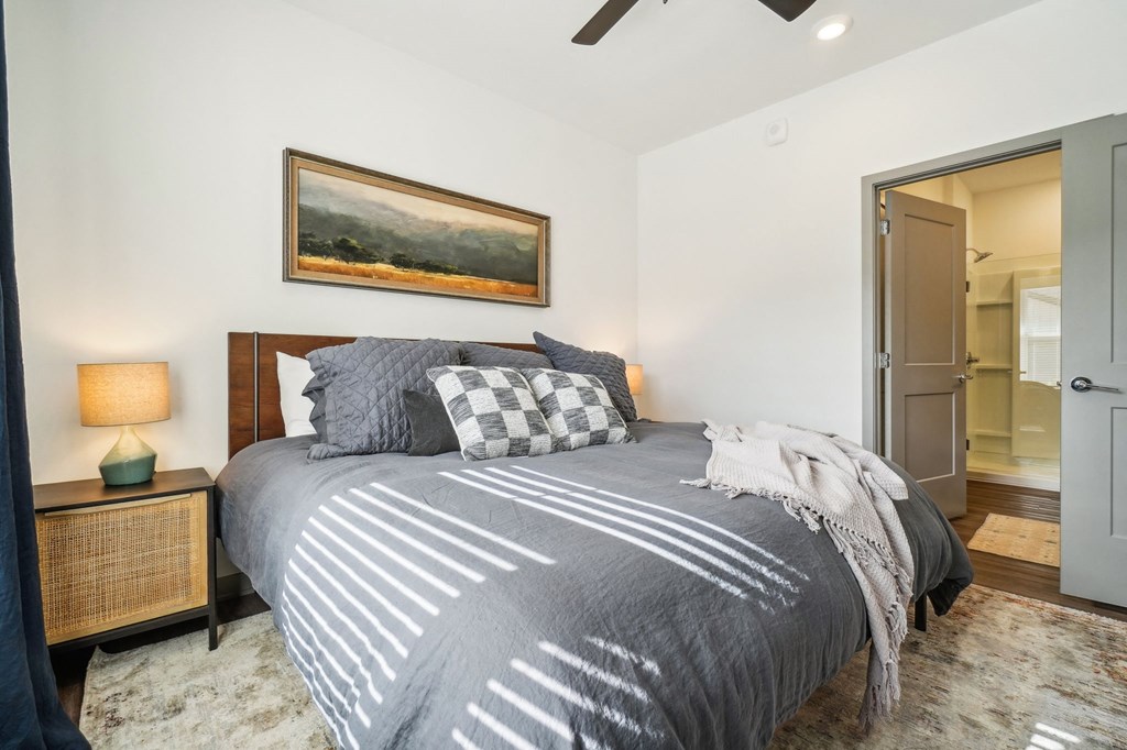 a bedroom with a bed and a door to a bathroom at Premier at West Park Luxury Apartment Homes, Greeley, CO