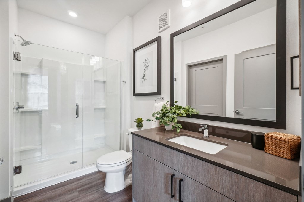 a bathroom with a mirror and a toilet and a shower at Premier at West Park Luxury Apartment Homes, Greeley, CO