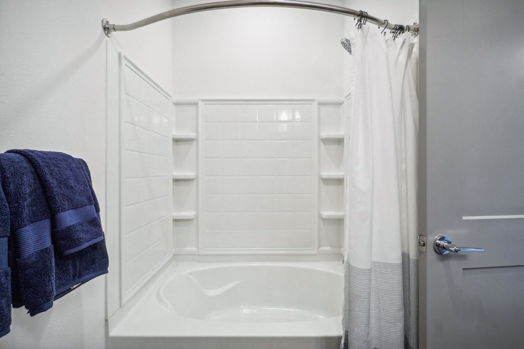 a small white bathroom with a shower and a tub at Premier at West Park Luxury Apartment Homes, Greeley, CO