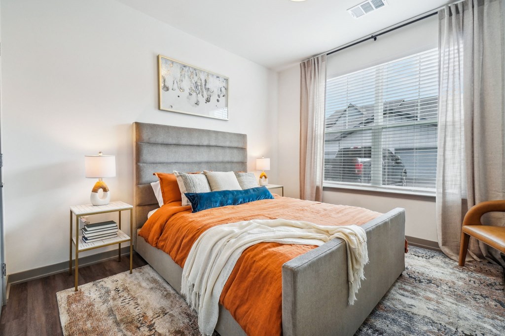 a bedroom with a large window and a bed with an orange blanket at Premier at West Park Luxury Apartment Homes, Greeley, 80634