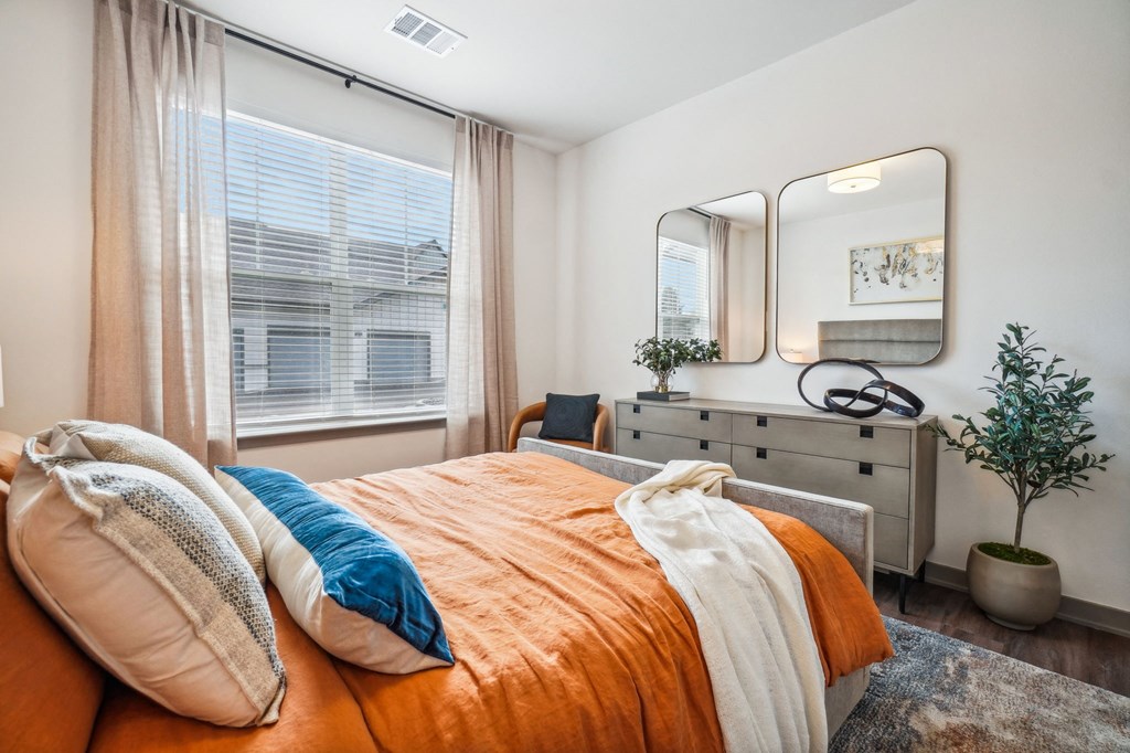 a bedroom with a bed and a dresser with a mirror at Premier at West Park Luxury Apartment Homes, Greeley, 80634