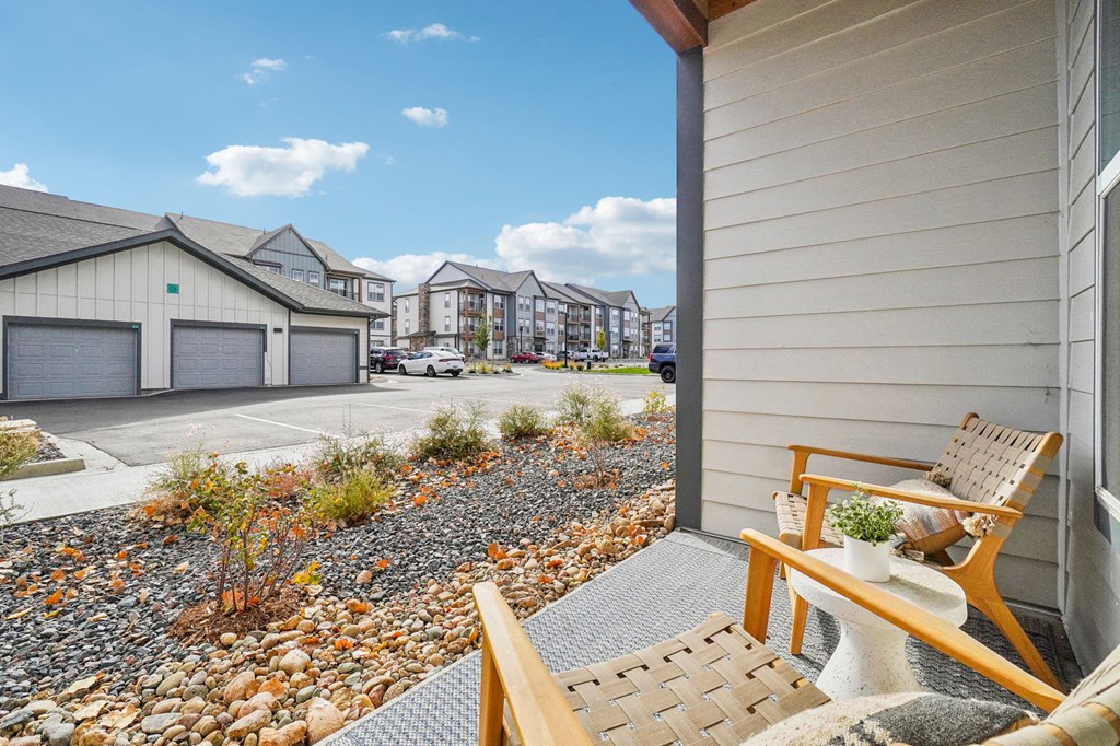 the front porch of a house with a chair and a gravel yard at Premier at West Park Luxury Apartment Homes, Greeley, CO