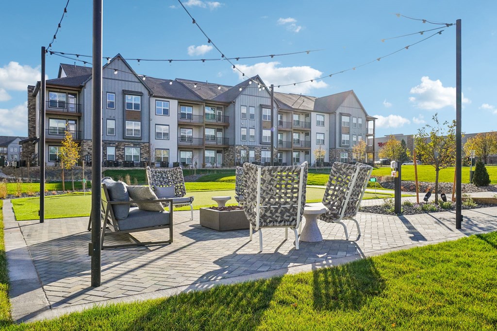 a patio with chairs and a table in front of an apartment building at Premier at West Park Luxury Apartment Homes, Greeley, CO