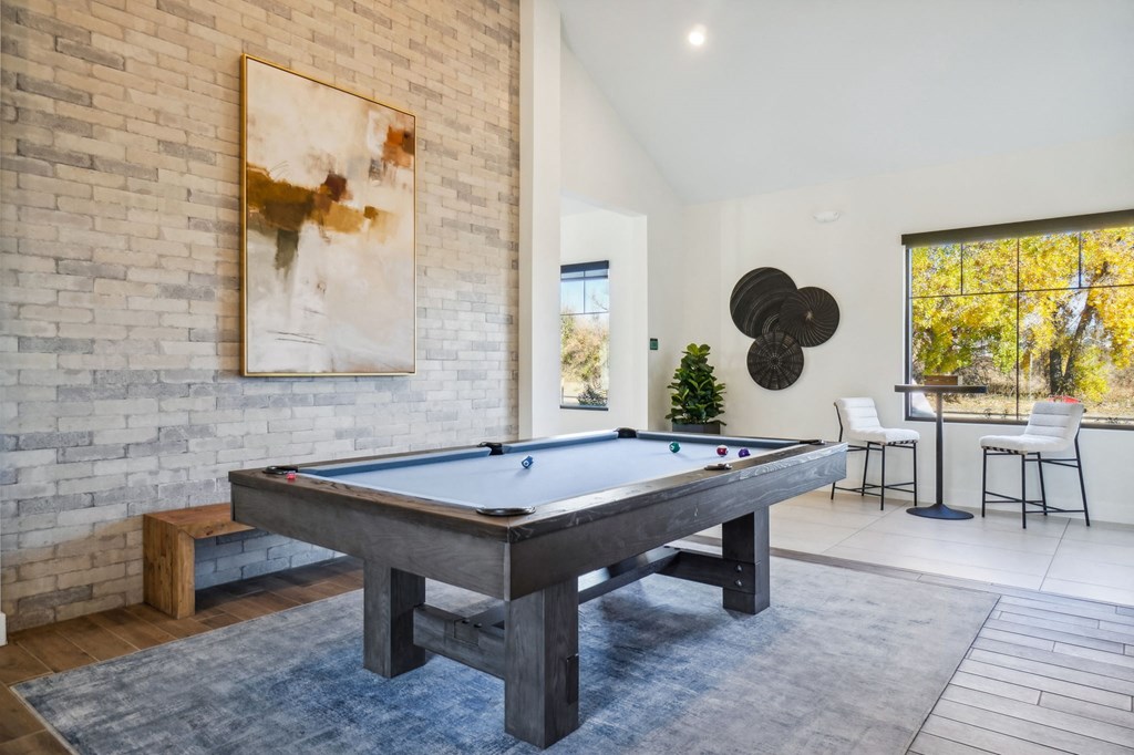 a pool table in a living room with a brick wall at Premier at West Park Luxury Apartment Homes, Greeley, CO, 80634