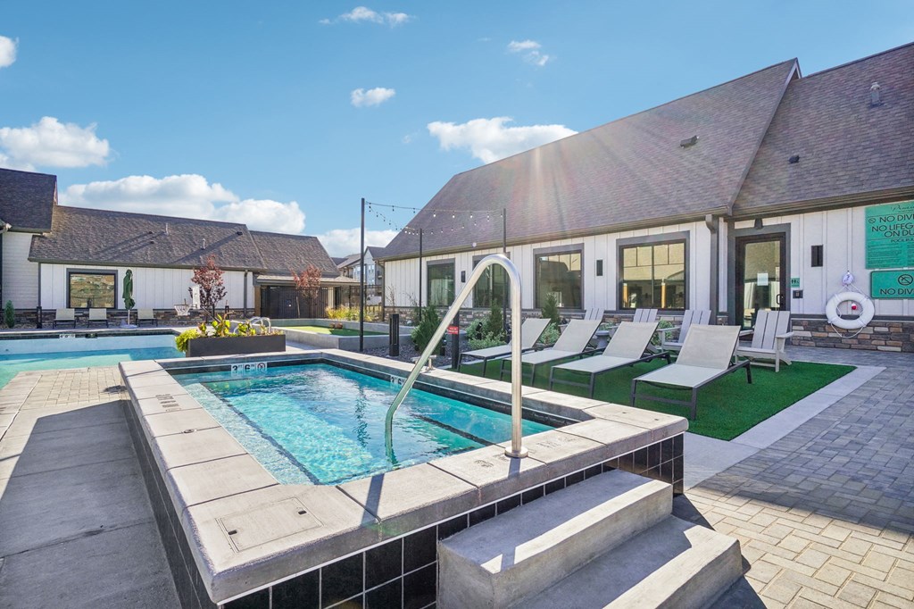 a swimming pool in front of a house with a pool and lounge chairs at Premier at West Park Luxury Apartment Homes, Greeley, CO