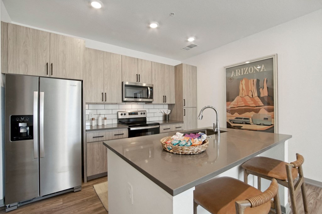 a kitchen with stainless steel appliances and a large island with bar stools at The Maddox Luxury Apartment Homes, Buckeye Arizona
