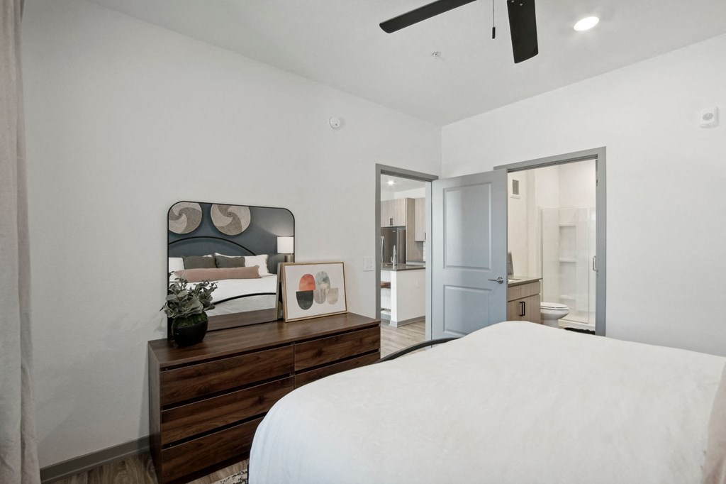 a bedroom with a large white bed and a wooden dresser at The Maddox Luxury Apartment Homes, Buckeye Arizona