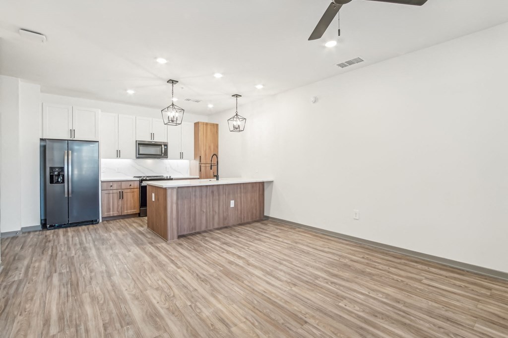 a kitchen and living room with wood flooring and a stainless steel refrigerator at The Maddox Luxury Apartment Homes, Buckeye, AZ