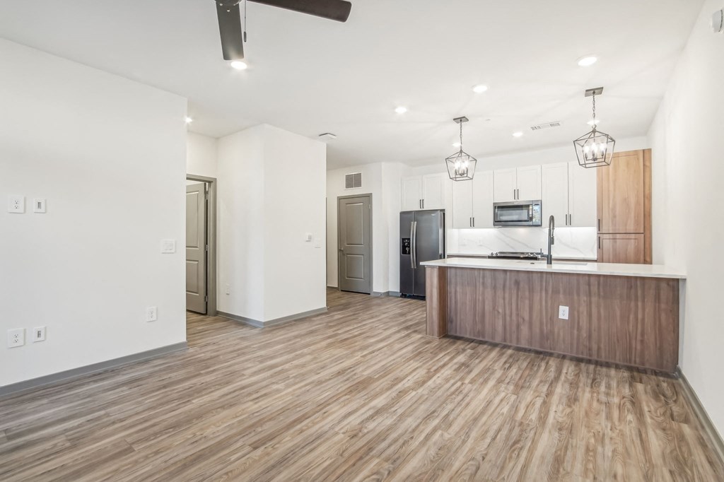 a kitchen and living room with white walls and wood floors at The Maddox Luxury Apartment Homes, Buckeye, AZ
