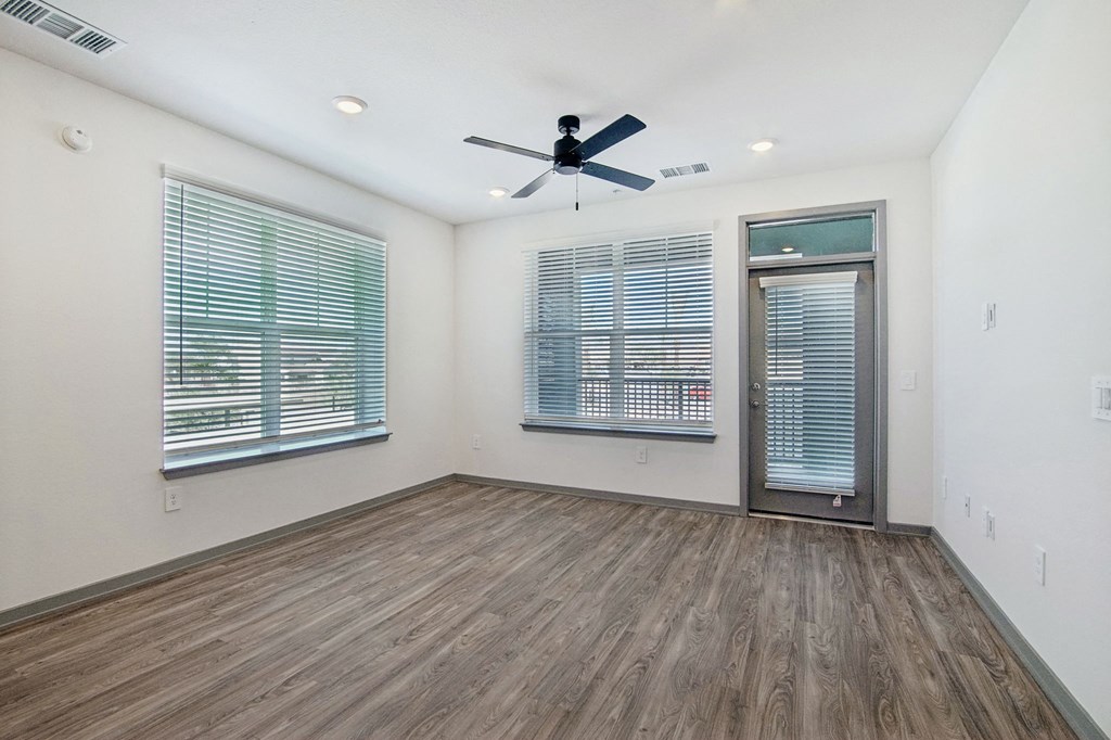 an empty living room with a ceiling fan and two windows at The Maddox Luxury Apartment Homes, Arizona