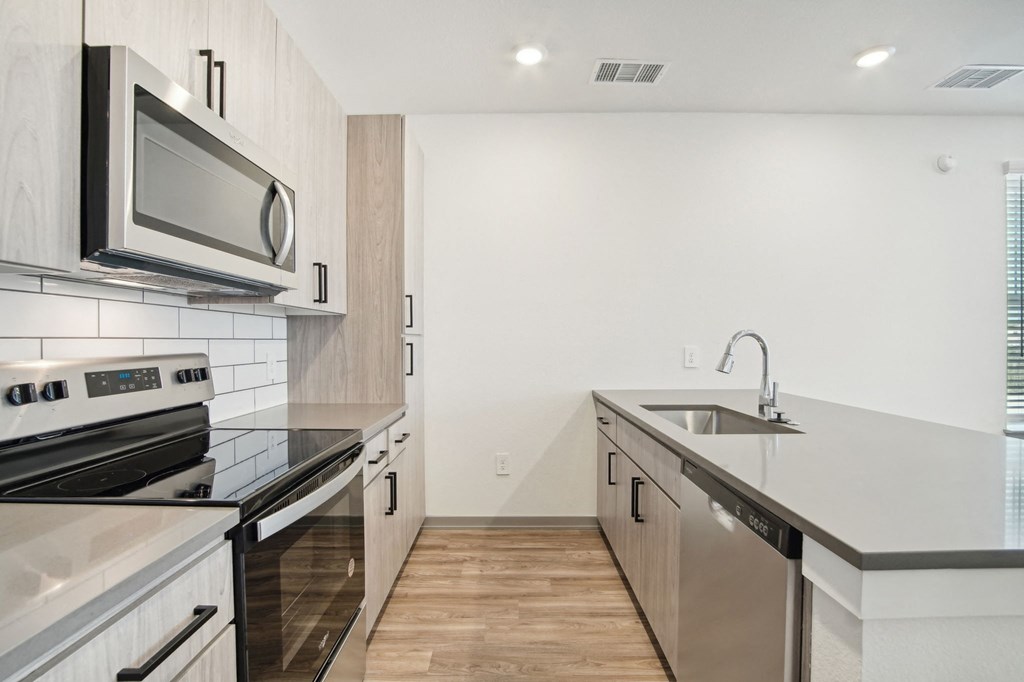 an empty kitchen with stainless steel appliances and black counter tops at The Maddox Luxury Apartment Homes, Buckeye Arizona