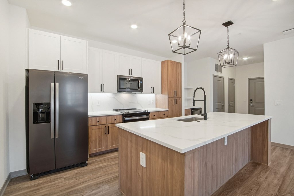 a kitchen with a large island and a stainless steel refrigerator at The Maddox Luxury Apartment Homes, Buckeye, AZ 85326