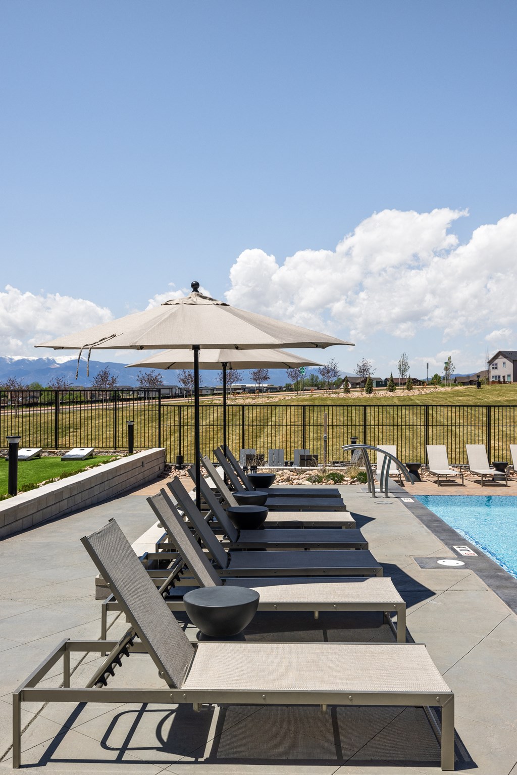 a row of lounge chairs and an umbrella on a pool deck
