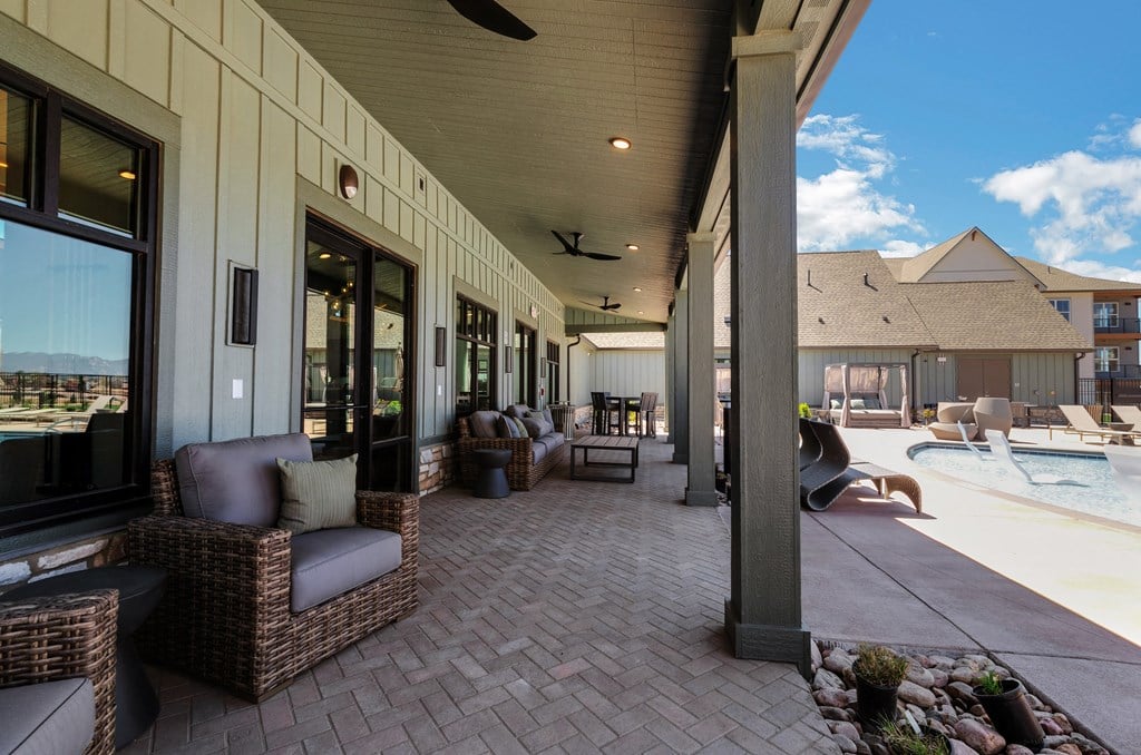 a covered patio with wicker furniture and a pool in the background  at Upland Flats, Colorado, 80922