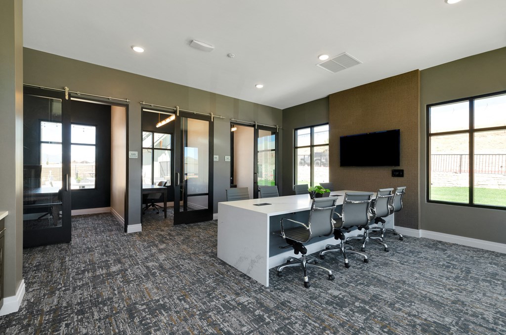 an open office space with a large desk and chairs and a flat screen tv on the wall  at Upland Flats, Colorado Springs, 80922