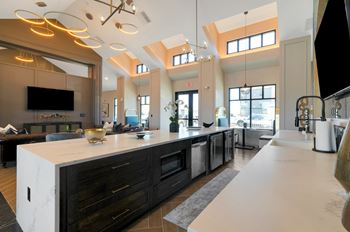 a kitchen with a large center island with a breakfast bar and a living room in the background  at Upland Flats, Colorado Springs, 80922