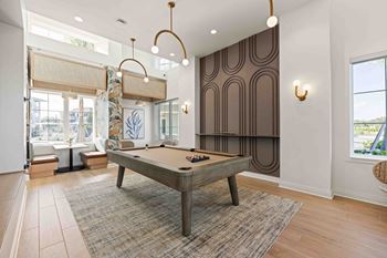 A pool table is in the middle of a room with a brown carpet.