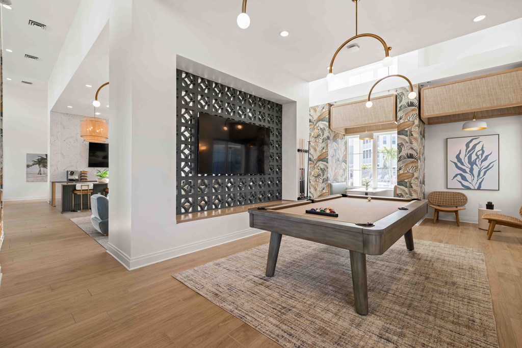 A pool table is in the middle of a room with a television and a chair.