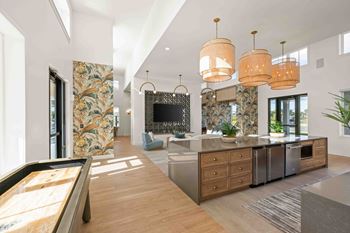 A modern kitchen with a pool table in the middle.