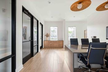 A modern office with a glass wall and a wooden floor.