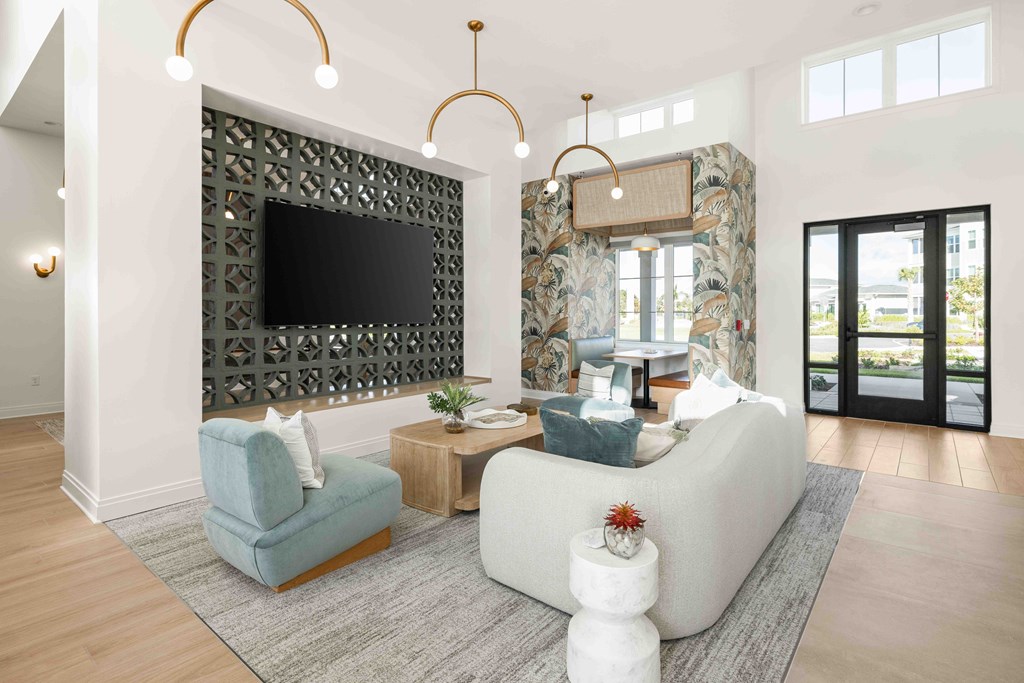 A living room with a grey sofa, a blue armchair, a wooden side table, a television, and a large window.