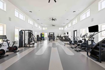 A spacious gym with a variety of exercise equipment and a person working out.