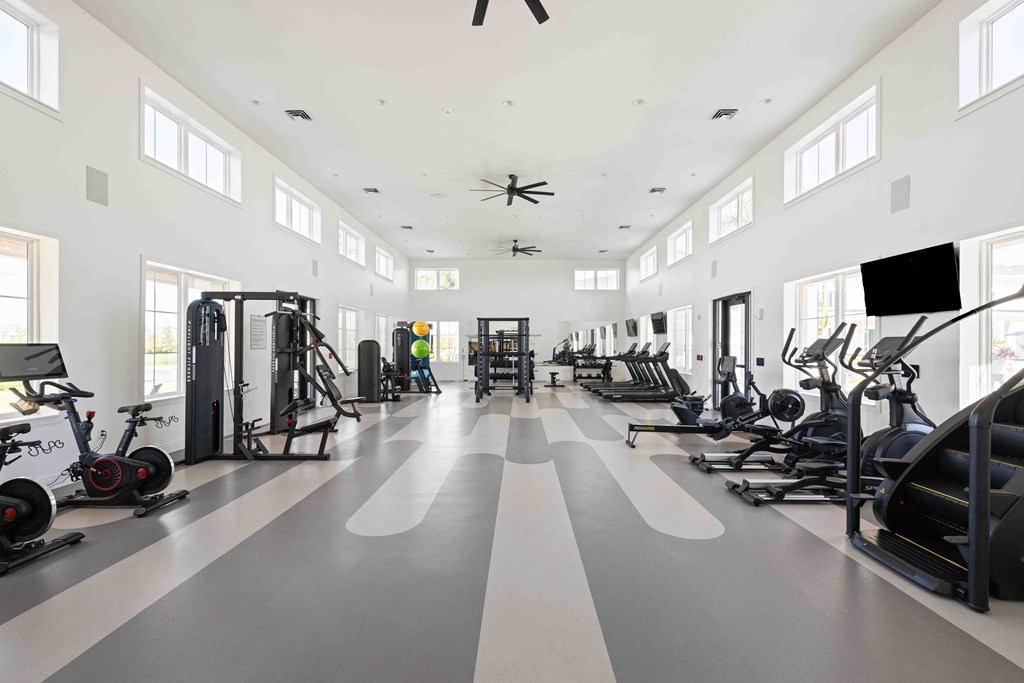 A spacious gym with a variety of exercise equipment and a person working out.