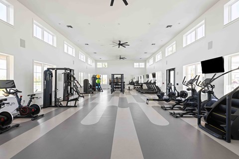 A spacious gym with a variety of exercise equipment and a person working out.