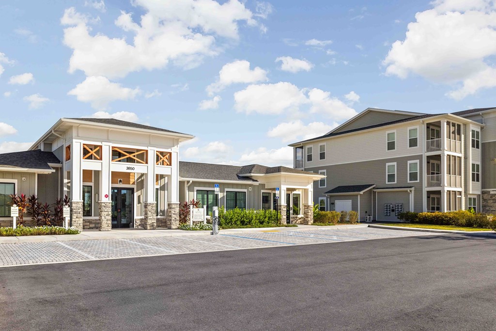 A large building with a covered entrance and a parking lot in front.