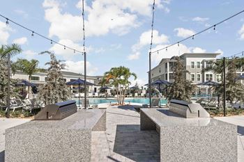 A park with a bench and a pool in the background.