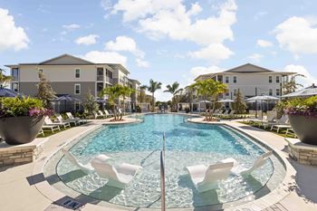 A large outdoor pool with a waterfall and lounging chairs.