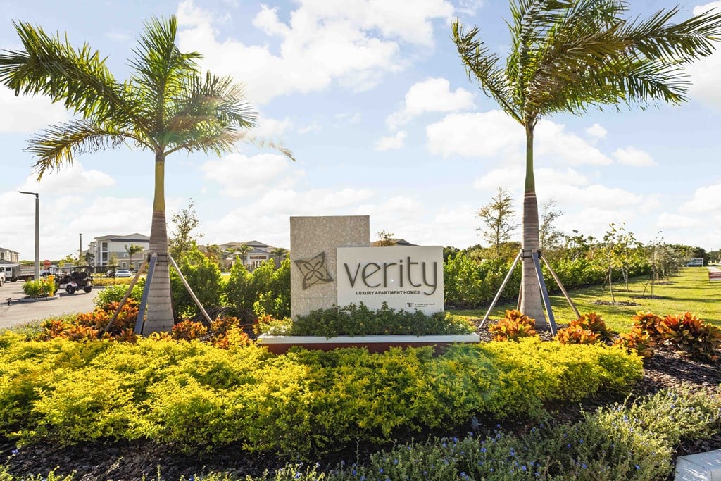 A sign that says "verity" is in front of two palm trees.