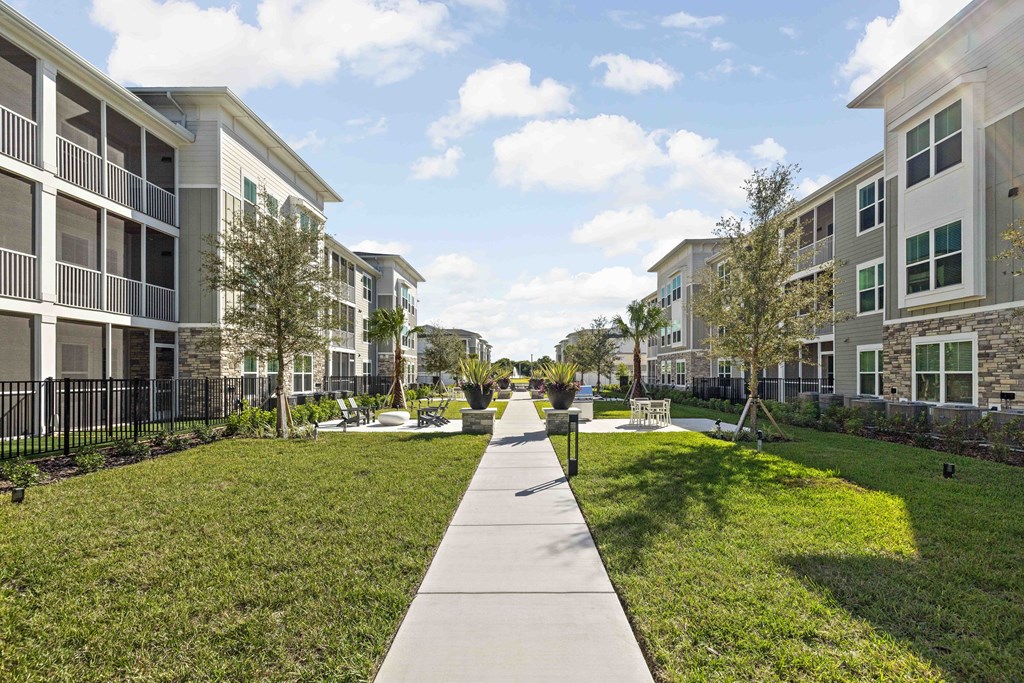 A walkway in the middle of a grassy area with apartment buildings on either side.