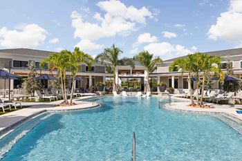 A large swimming pool in front of a building with palm trees.