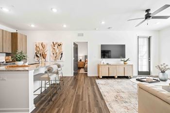 A modern living room with a kitchen area in the background.