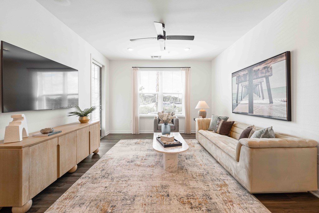 A living room with a rug, a couch, a coffee table, and a painting on the wall.