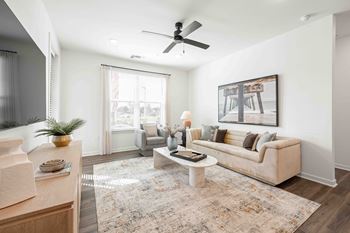 A living room with a beige couch, a rug, and a painting on the wall.