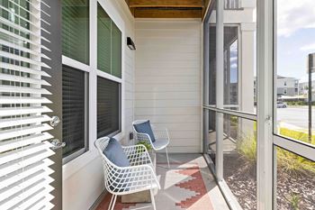 A white chair with a blue pillow is on a porch.